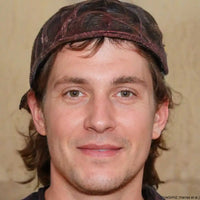A smiling man with brown hair and a backwards baseball cap.